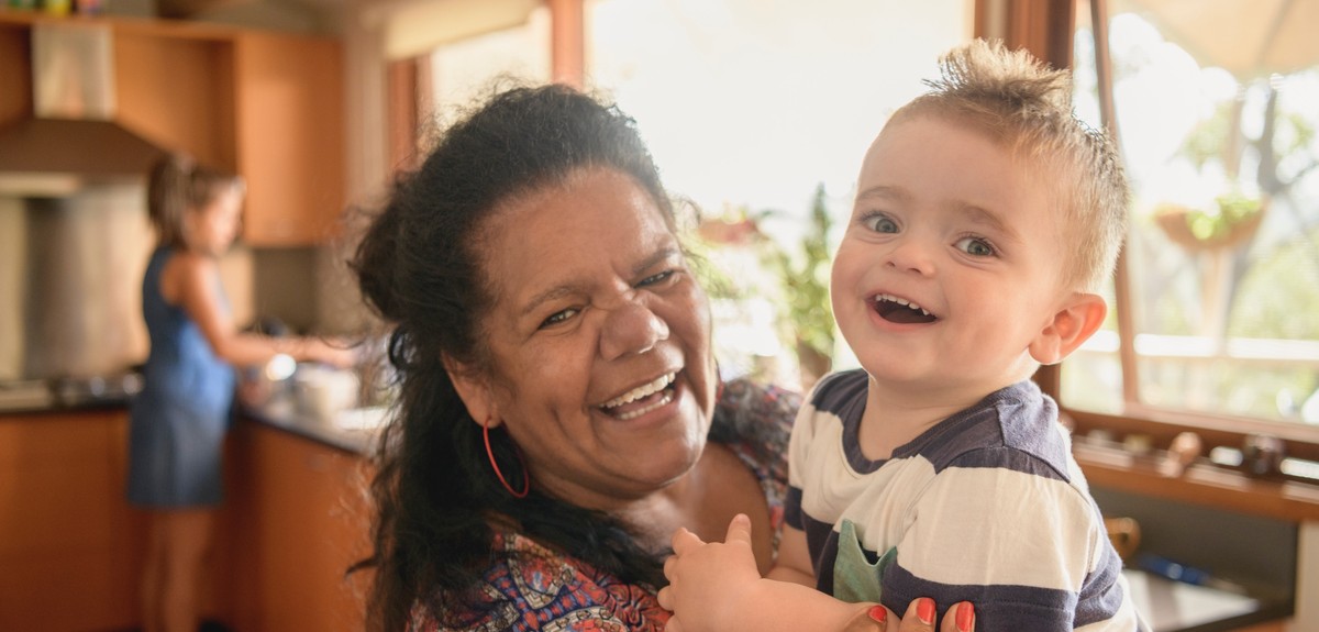 Female foster carer smiling and holding her toddler grand-son
